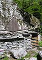 Adding a dry stone wall to convert the space under a large rock into a functional building near Bignasco, Switzerland
