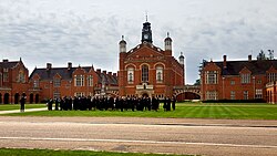 Uniformed pupils assembled on the grass amid red brick school buildings