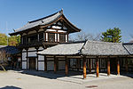 Two-storied wooden building with white walls and an attached open veranda with handrail on the upper floor.