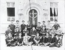 Three rows of Pontic Greek men and boys in front of a school. They wear western suits.
