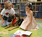 A 9-year-old student reading alongside a therapy dog. Those raised in the 2000s and 2010s are much less likely to read for pleasure than prior generations.