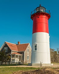 Red and white lighthouse next to a house