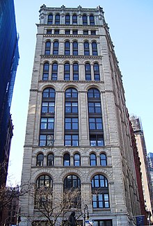 A multi-story white Romanesque building, seen looking up from street level