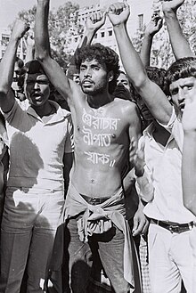 Hossain with other people, with his shirt off to display a message translating to "down with autocracy" painted on his chest.