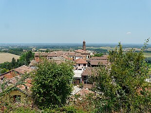 Photo shows village rooftops in the foreground. In the background, it can be seen that the surrounding country is all at lower elevation.