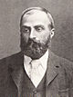 A middle-aged bearded man wearing a tie, waistcoat and jacket.