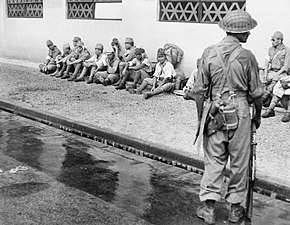 Indian soldier guards Japanese prisoners in Singapore