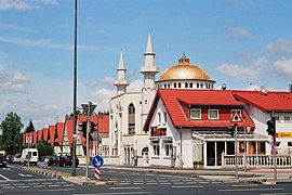 Moschee mit umgebender Architektur, im Vordergrund der türkische Imbiss