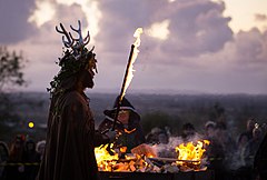 A neopagan holding a torch at a Samhain celebration