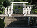 White torii beyond concrete fence.