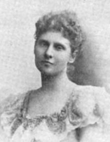 A young white woman wearing a gown with a square ruffled neckline