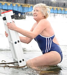 Woman going ice swimming, having entered halfway into the water