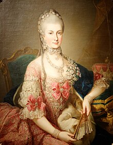 Young woman wearing an elaborate pink dress with white lace, pink ribbons, and diamond jewellery. There is a fan in her hand; she is seated before a plain background, looking directly at the viewer. Her hair is long and powdered white.