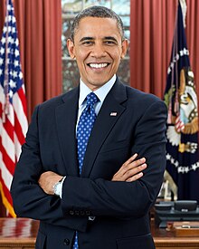 Obama standing with his arms folded and smiling