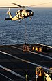 Sailors on the flight deck of Ronald Reagan stand by as an SH-60F Seahawk assigned to the Black Knights Helicopter Anti-Submarine Squadron 4 delivers cargo during a vertical replenishment.