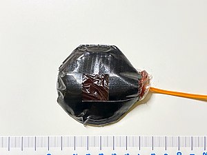 A bullet hit squib device with approx. 25 g of fake blood in a plastic pouch, assembled with duct tape.