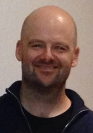 A bald middle-aged man smiling at the camera