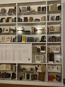 Eight bookshelves stacked on top of each other containing translations of the Divine Comedy arranged for display