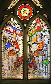 Two men in armour stand opposite each other. They wear crowns and hold swords in their hands. Above the man on the left is a flag of a white boar and a white rose. Above the man on the right is a flag of a red dragon and a red rose. Above and between the two roses is a white rose superimposed on a red rose.