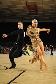A latin ballroom couple perform a Samba routine at a dancesport event.