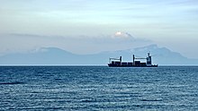 A container ship, Selatan Damai, anchored off Dili, East Timor, in 2018 with Atauro in the background