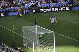 View from behind the goal of Messi with the ball, while two German defenders chase him and the goalkeeper stands guard