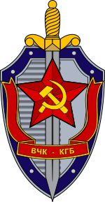 A sword over a shield, and a ribbon with Russian text on it. There is a red star with a hammer and sickle on the center of the sword.