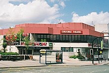 an exterior shot of a theatre with a red roof