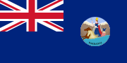 A British blue ensign with the Union Jack in the upper-left corner and a colonial seal in the lower-right.