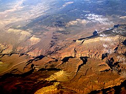 Aerial view – WNW of The Esplanade (Grand Canyon), south bank of Colorado River, with Toroweap Fault–(Prospect Canyon) as west border Uinkaret volcanic field at NW; Lava Falls below in Colorado River
