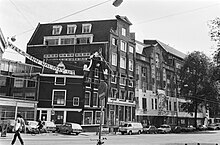 Black and white photograph of assorted buildings in the Wyers complex with a banner which reads "Wyers Inn Holiday Uit", a play on words saying "Wyers In, Holiday Inn out!"