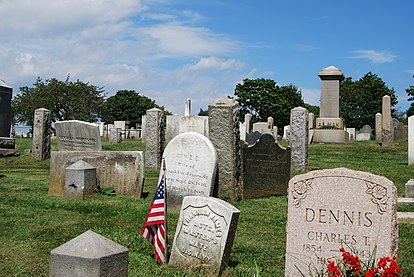 Tombstones (funerary stelae) at the Common Burying Ground and Island Cemetery, Newport, Rhode Island. Typical inscriptions include the names of the deceased interred under the stones. c. 18th century and later.