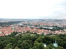 Photo taken from the top of Petřín Tower which shows the city of Prague you can see the rivers with the bridges. The iconic red roofs of Prague dominate the image.