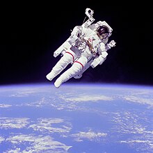 An astronaut in a spacesuit seen against the background of the Earth as seen from space