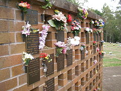 Columbarium wall, with flowers, plaques, and empty niches
