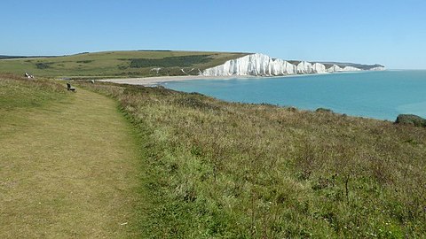 A photograph which illustrates that on Short Cliff above Cuckmere Haven, the Vanguard Way follows a coastal path. The widely known Seven Sisters chalk cliffs are shown in the distance.