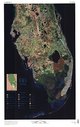 A color satellite image of the lower two-thirds of the Florida peninsula: large bodies of water are black, most chunk of land south of Lake Okeechobee is red, indicating the Everglades Agricultural Area; south of that is a solid swath of dark blue indicating where the Everglades flow in a southwesterly direction into the Gulf of Mexico
