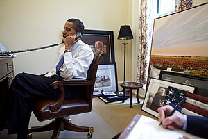Barack Obama speaks into a telephone in the Oval Office Study
