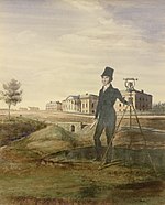 Man standing on hill beside large measuring instrument with building in background