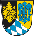 Landkreis Unterallgäu Durch eine eingeschweifte, gesenkte silber-blau gerautete Spitze gespalten von Schwarz und Gold, vorne eine goldene Rosette, hinten eine blaue Lilie.