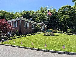 Flower Hill Village Hall in 2023, with flags on the lawn to celebrate Memorial Day.