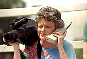 Journalist Lucy Morgan holding one of the first brick mobile phones, as well as a 1980s video camera