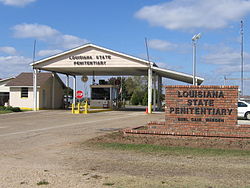 The entrance to the Louisiana State Penitentiary has a guard house that controls entry into the compound—the sign says "Louisiana State Penitentiary" and "Burl Cain, Warden"
