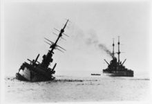 A battleship leaning heavily to the right, about to capsize