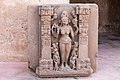 Göttin Durga(?) auf einer Lotosblüte stehend, begleitet von Dienerinnen und gerahmt von zwei reich dekorierten Pfeilern mit kalasha-Motiven