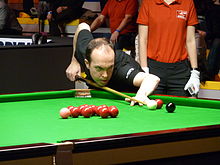 Fergal O'Brien leans across a snooker table holding his cue lining up a shot to a corner pocket