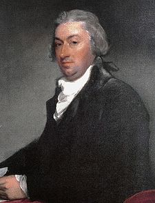 An oil portrait of a clean-shaven older man, seated, wearing a black robe and white neck ruff
