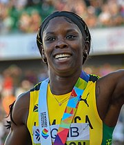 Die 200-Meter-Weltmeisterin Shericka Jackson winkt mit umgehängter Medaille ins Publikum.