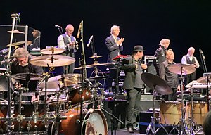 King Crimson at the Sapporo Culture Arts Theatre in Japan, on 2 December 2018. Bottom L-R: Pat Mastelotto, Jeremy Stacey, and Gavin Harrison. Top L-R: Tony Levin, Bill Rieflin, Jakko Jakszyk, and Robert Fripp (Mel Collins not shown from the left)