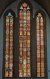 Buntglasfenster aus dem 14. Jahrhundert im Chor; im dreiteiligen Fenster findet sich links ganz unten sowie auch links in der Mitte das Vorbild der Lutherrose